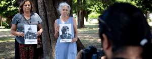 imagen de dos mujeres sosteniendo fotografías de personas en blanco y negro